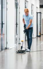 Avaleht 5 Young man works in the modern office. Uses vacuum cleaner.